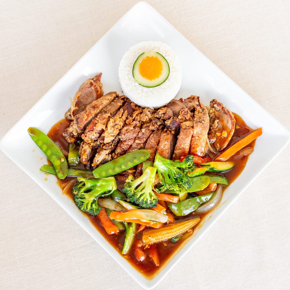 Crispy sliced meat with steamed rice and stir-fried vegetables in brown sauce on a white plate.